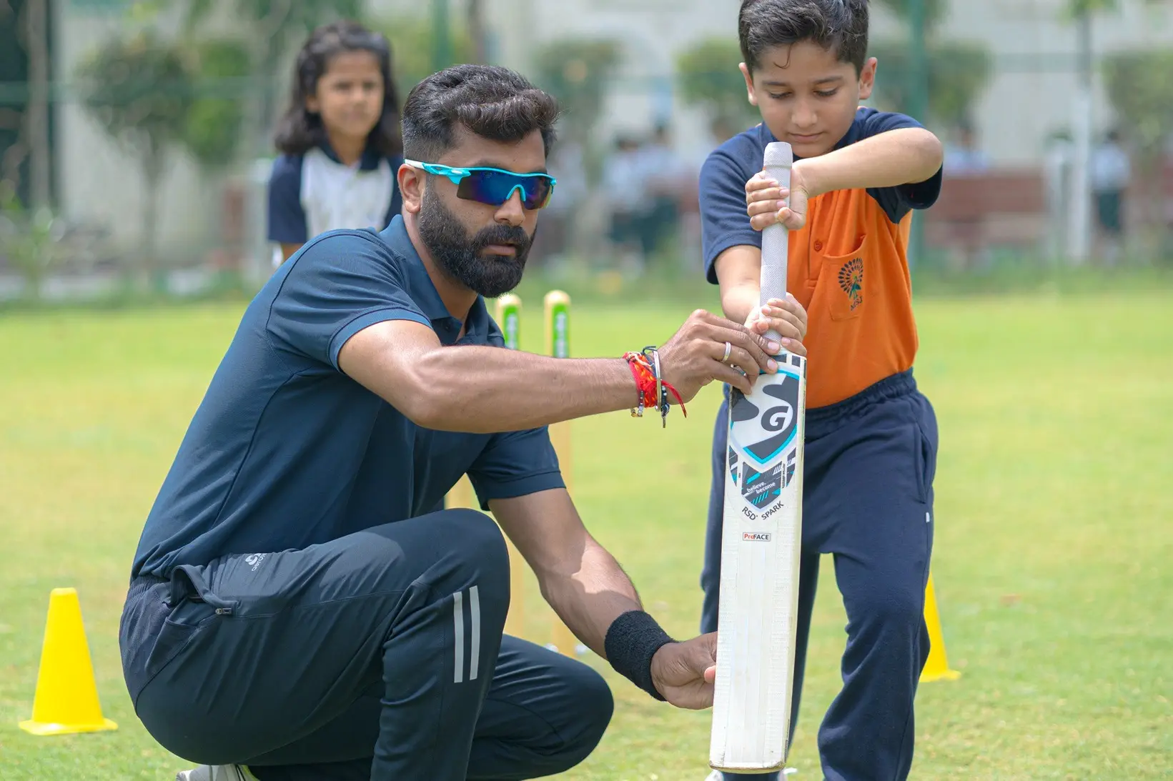 coach is giving instructions to student while playing cricket